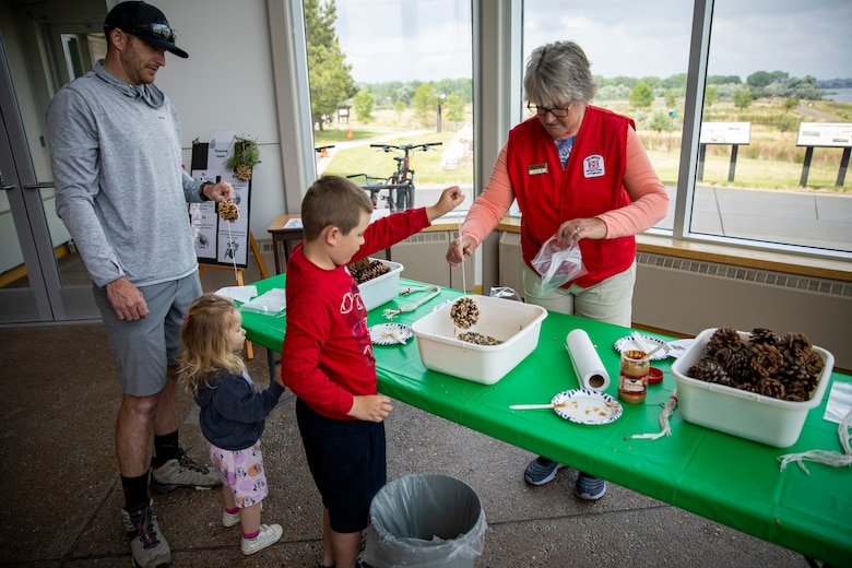A volunteer at the U.S. Army Corps of Engineers’ Fort Peck Interpretive Center and Museum in Fort Peck, Montana, helps young visitors create pinecone bird feeders, June 21, 2025, during the center’s 20th anniversary celebration.