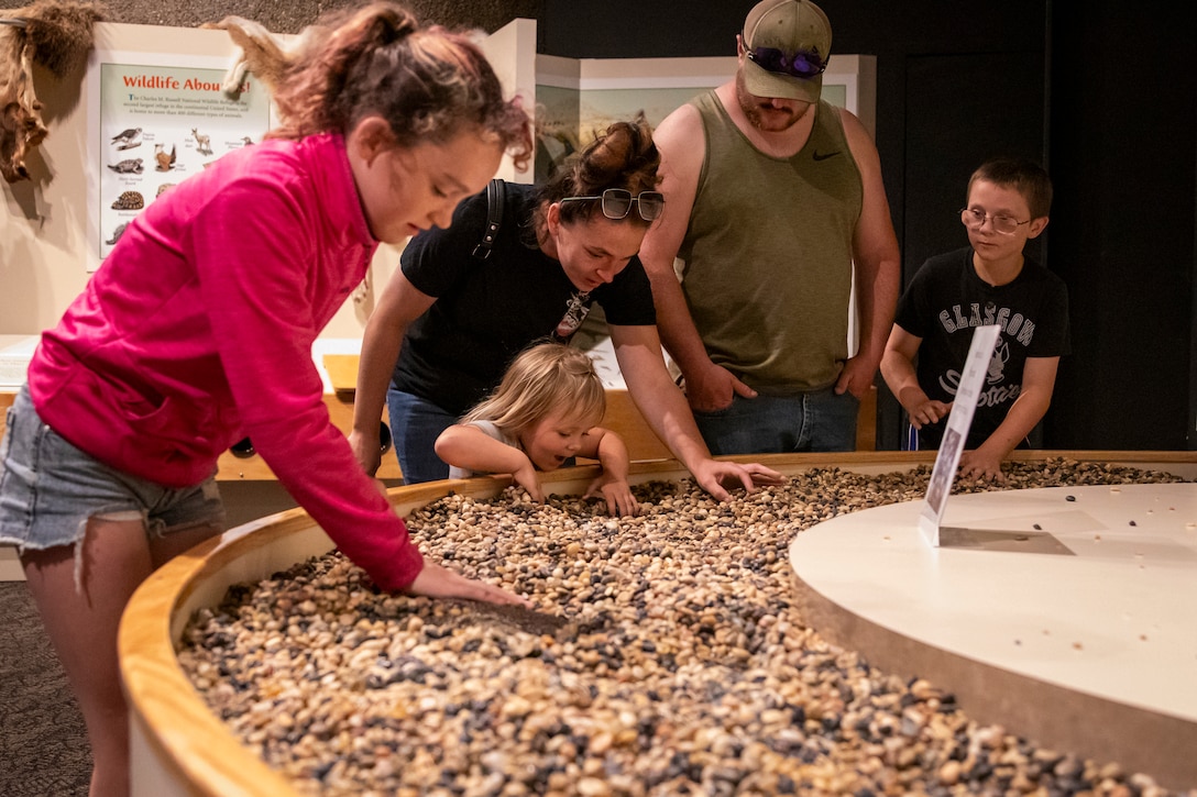 A family of visitors expose fossils buried under rocks in a hands-on exhibit at the U.S. Army Corps of Engineers’ Fort Peck Interpretive Center and Museum in Fort Peck, Montana, June 21, 2025, during its 20th anniversary celebration.