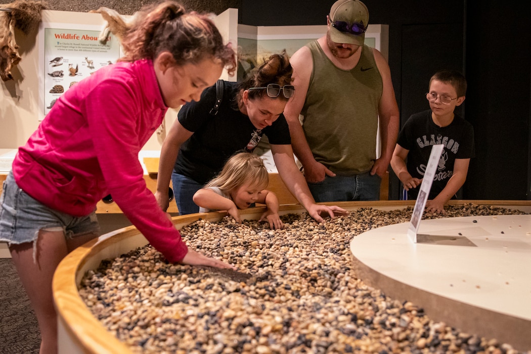 A family of visitors expose fossils buried under rocks in a hands-on exhibit at the U.S. Army Corps of Engineers’ Fort Peck Interpretive Center and Museum in Fort Peck, Montana, June 21, 2025, during its 20th anniversary celebration.