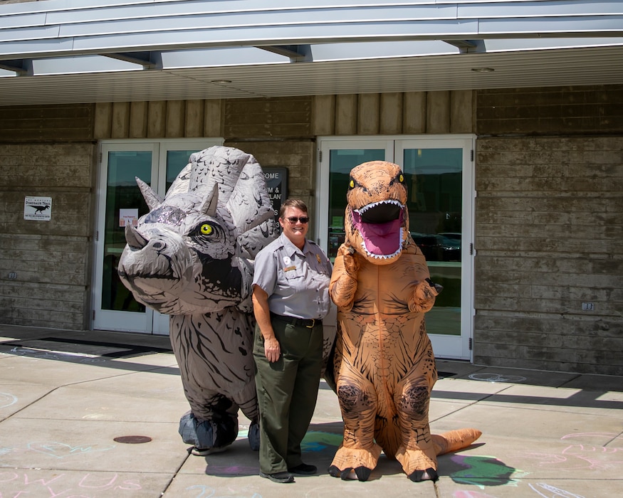Cindee Parker, U.S. Army Corps of Engineers natural resource specialist, poses with two prehistoric visitors (volunteers in inflatable dinosaur costumes) at the Fort Peck Interpretive Center and Museum, June 21, 2025, at Fort Peck, Montana, during its 20th anniversary celebration.