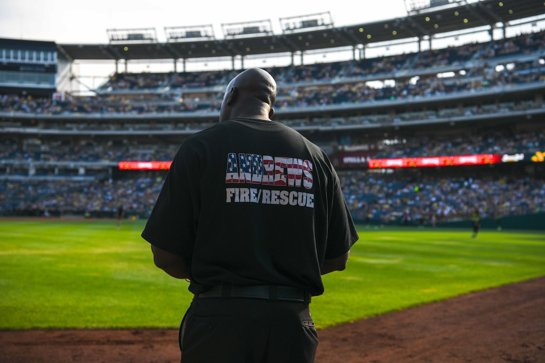 A firefighter stands on a baseball field.