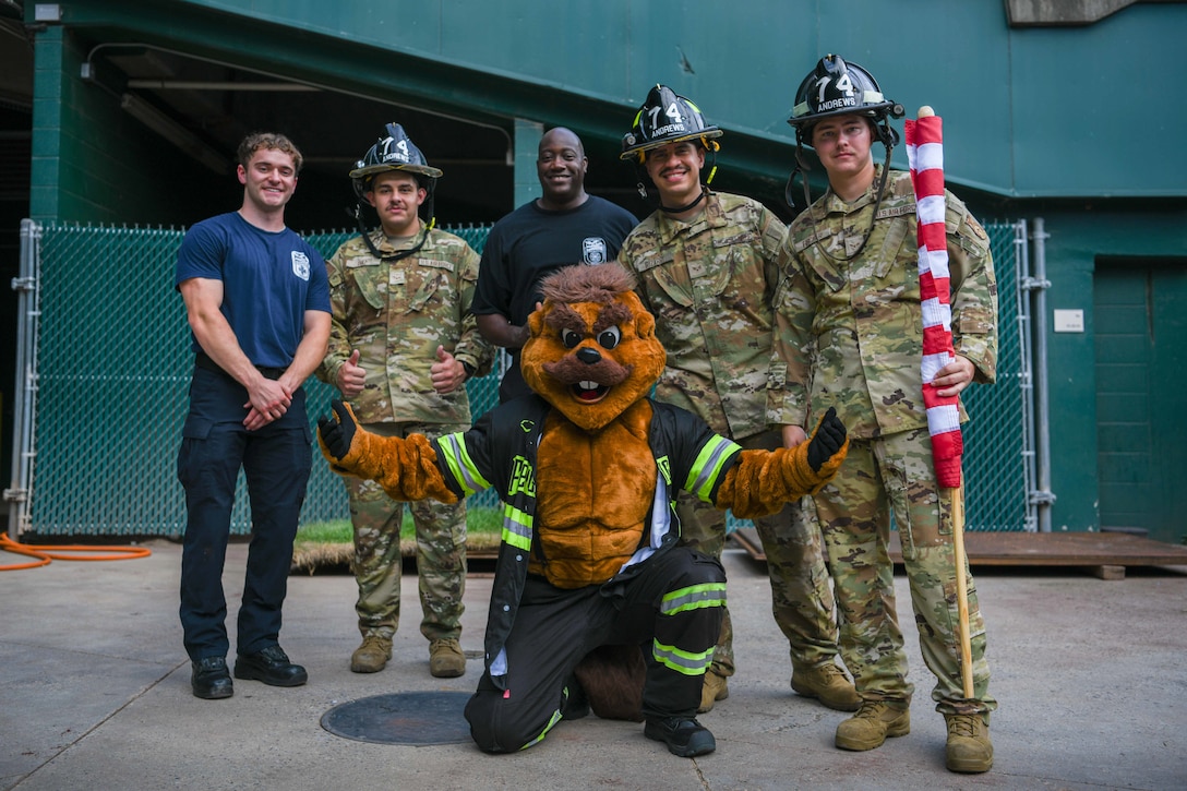 Service members and firefighter pose with a baseball mascot.
