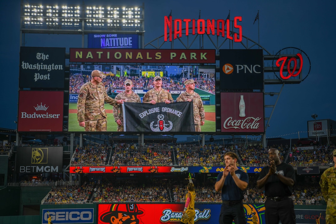 Airmen wave on a baseball field.