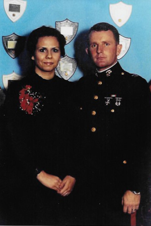 A Marine wearing a formal military uniform stands beside a woman.