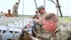 Airmen guide a munition down a conveyer belt.