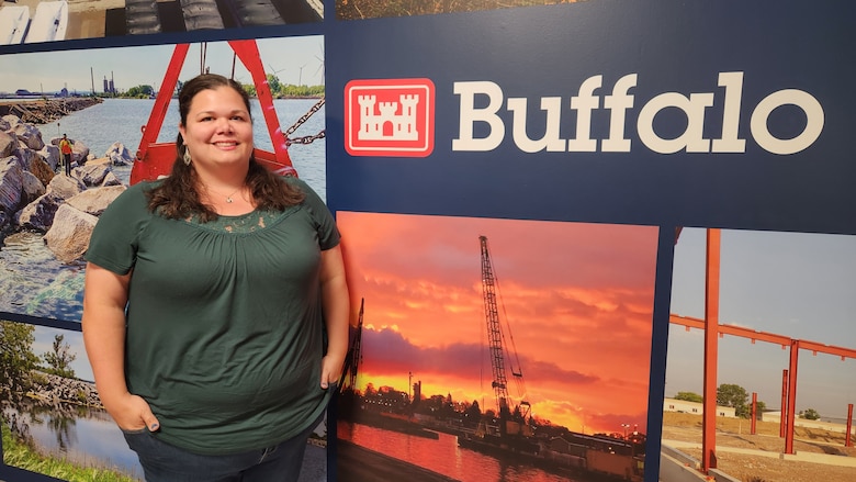 U.S. Army Corps of Engineers, Buffalo District Chief of Construction Contracting Administration Katie Lewis stands in front of a district highlight wall.