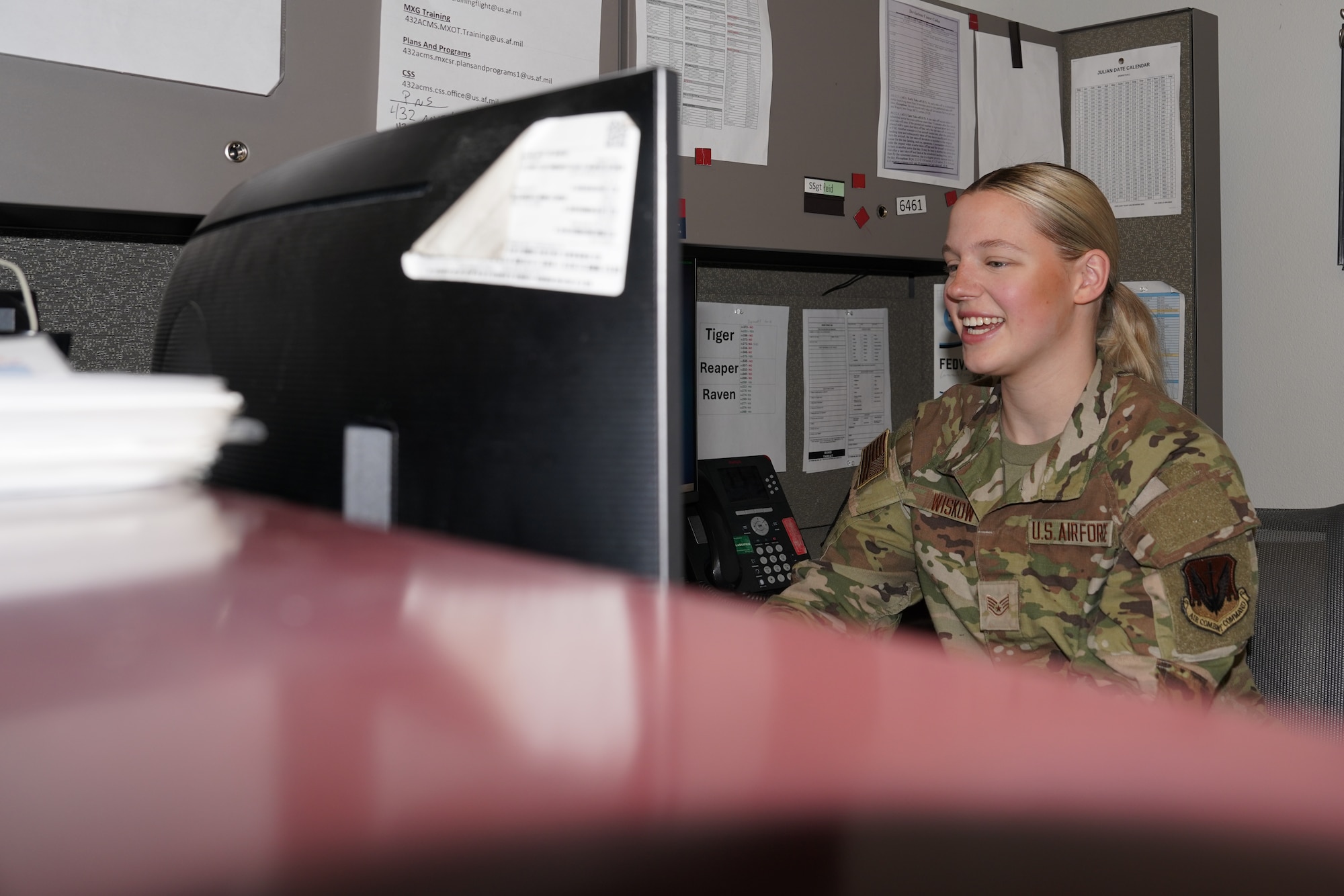 A woman in a military uniform works at a desk.