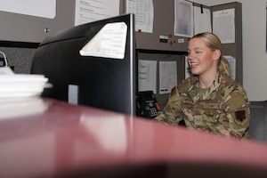 A woman in a military uniform works at a desk.