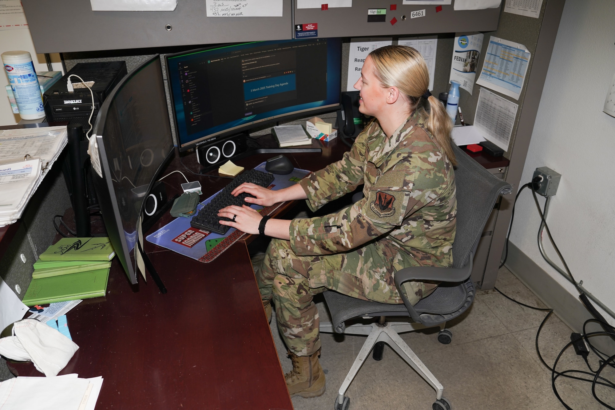 A woman in a military uniform works at a desk.
