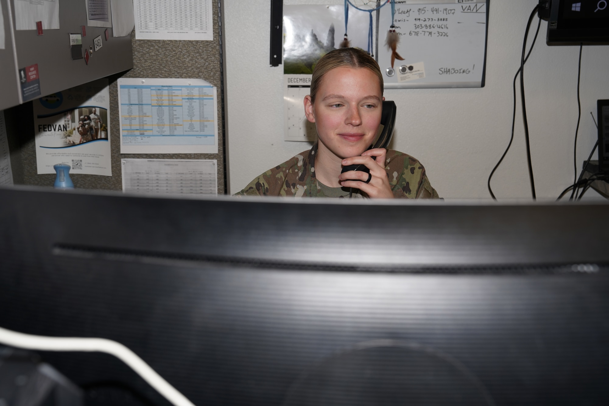 A woman in a military uniform answers a phone.