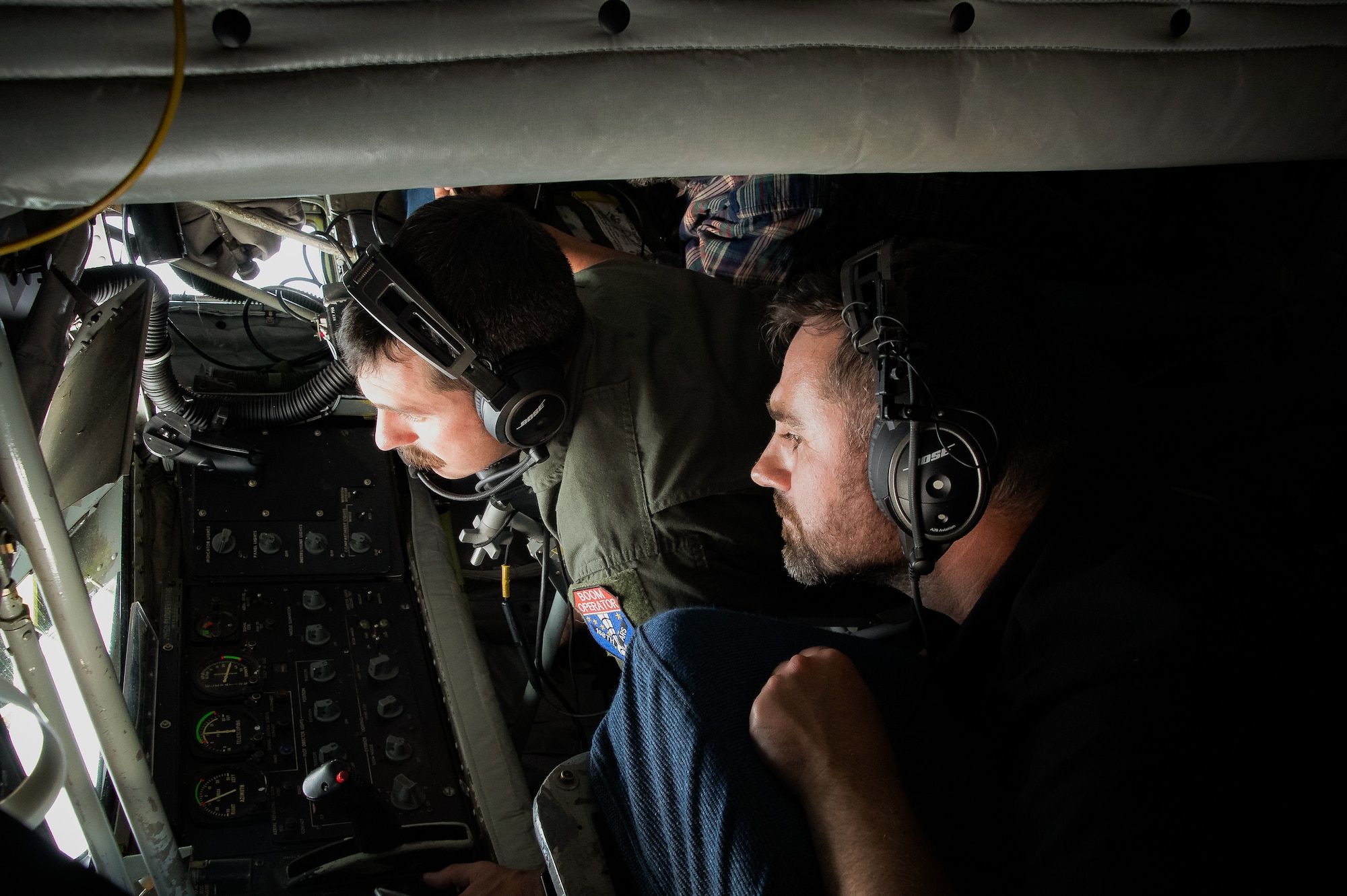Senior Master Sgt. Keith Rowan, boom operator with the 168th Air Refueling Squadron, Alaska Air National Guard, conducts an aerial refueling operation while Dean Baxter, from Fairbanks International Airport Operations, observes from the boom pod