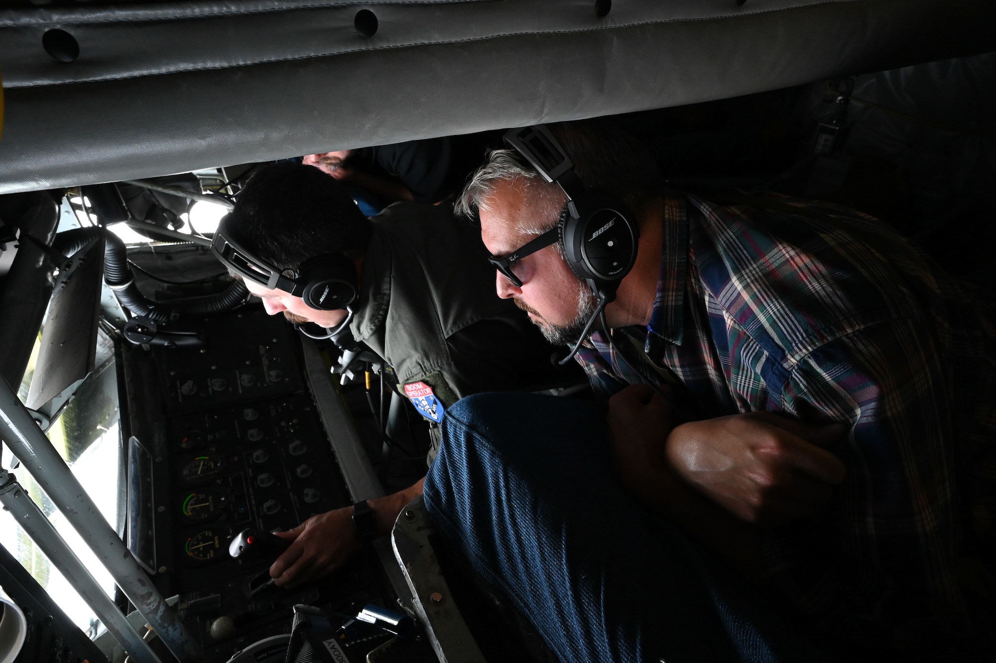 Senior Master Sgt. Keith Rowan, boom operator with the 168th Air Refueling Squadron, Alaska Air National Guard, conducts an aerial refueling operation while Dean Baxter, from Fairbanks International Airport Operations, and North Pole Mayor Larry Terch observe from the boom pod during a Civic Leader Flight