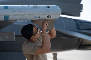U.S. Air Force Airman 1st Class Christian Slade, 18th Fighter Generation Squadron armament systems specialist, secures an inert AIM-120 Advanced Medium Range Air-to-Air Missile to a F-16 Fighting Falcon during the second quarter load competition at Eielson Air Force Base, Alaska, July 3, 2025.