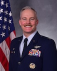 photo of uniformed US Airman standing in front of US flag