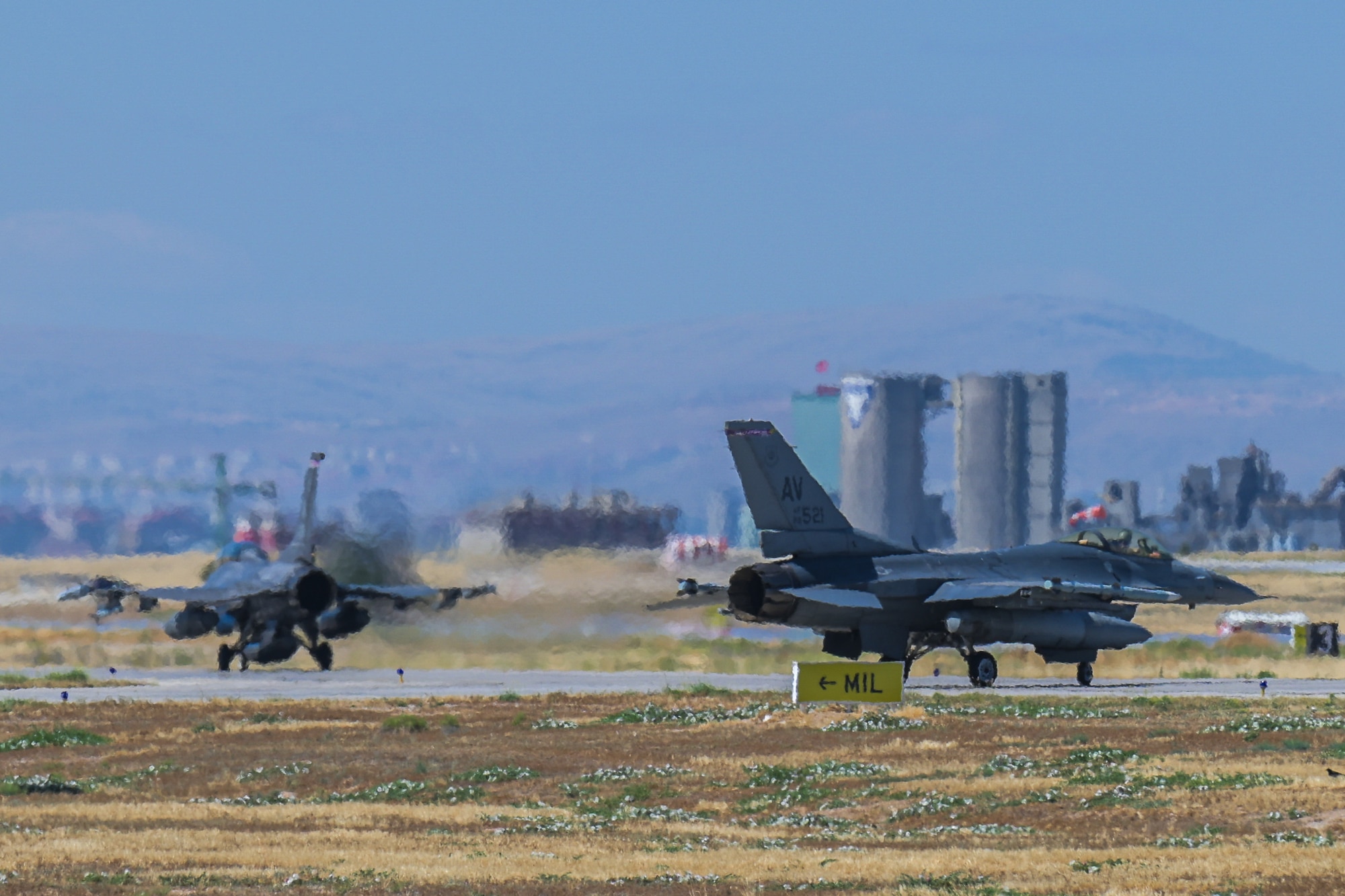 Two F-16s taxi down the runway.