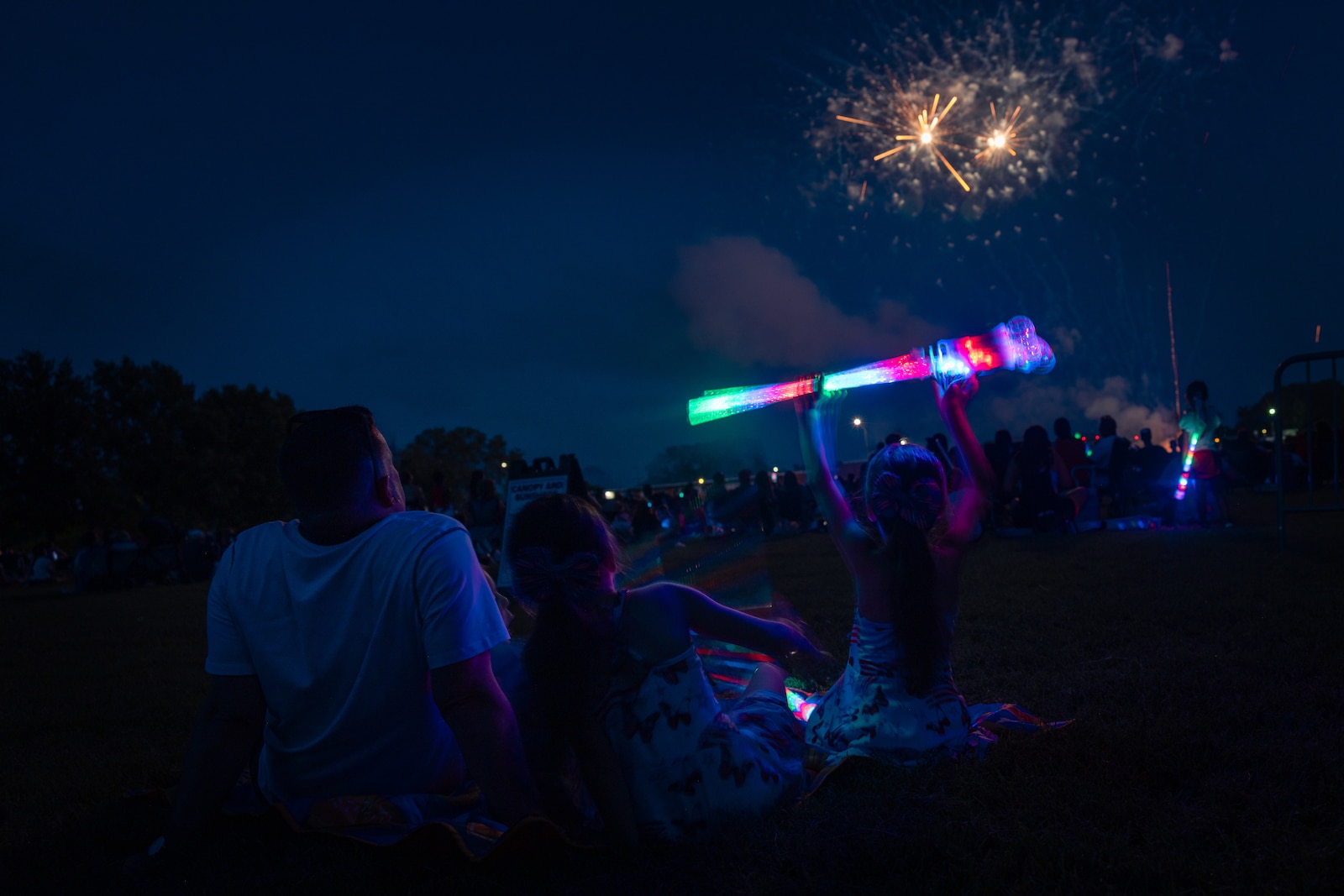 A family watches a firework show during Marine Corps Base Quantico’s Fourth of July celebration at Lejeune Field, MCB Quantico, Virginia, July 3, 2025. The event hosted a multitude of outdoor activities for families, friends and service members to include; bouncy house obstacle courses, a rock climbing wall, and games such as corn hole. The celebration featured a live performance from artist Huntley and ended in a firework show. (U.S. Marine Corps photo by Cpl. Darien Wright)