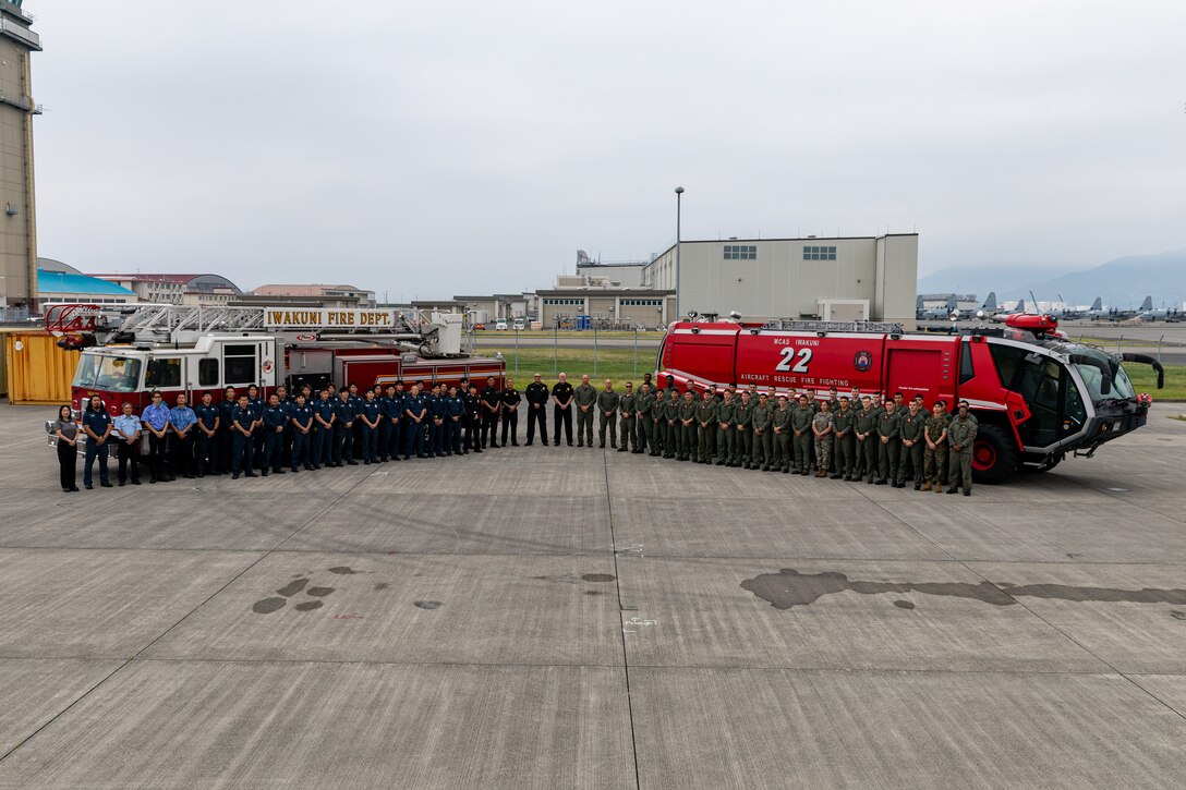 U.S. Marines with Aircraft Rescue and Firefighting, Headquarters and Headquarters Squadron, Marine Corps Air Station Iwakuni and Marine Labor Contractors with Fire and Emergency Services pose for a group photo at MCAS Iwakuni, Japan, June 9, 2025. Both ARFF and FES recently won the Medium Fire Department of the Year award for the third time in a row due to their outstanding performance and overall readiness for any situation that arises. (U.S. Marine Corps photo by Cpl. Dahkareo Pritchett)