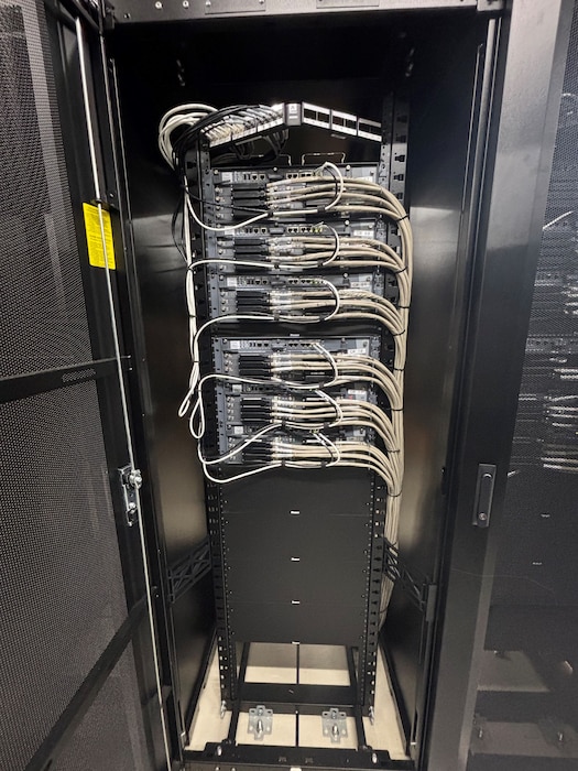 Photo of network cables in a distribution panel inside of a rack.
