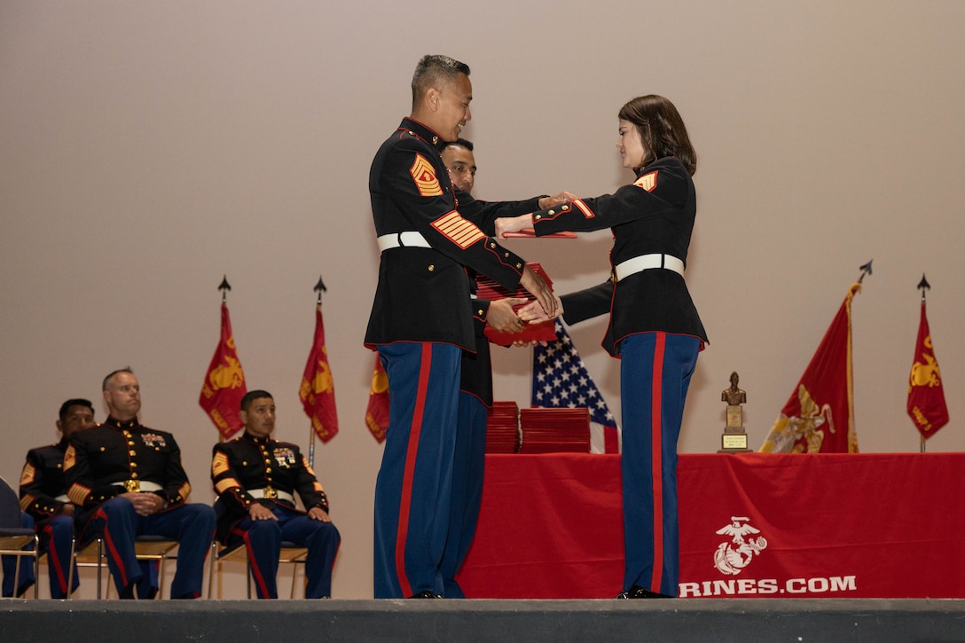 U.S. Marine Corps Master Gunnery Sgt. Michael R. Abragan, the chief instructor of Basic Recruiter's Course 3-25, gives the graduation certificates during a graduation ceremony at Marine Corps Recruit Depot San Diego, California, April 18, 2025. The mission of the BRC is to provide staff noncommissioned and noncommissioned officers with the basic skills and knowledge to successfully inform young men and women about the opportunities and career paths the Marine Corps offers. (U.S. Marine Corps photo by Lance Cpl. Genaro I. Valdez-Sepulveda)