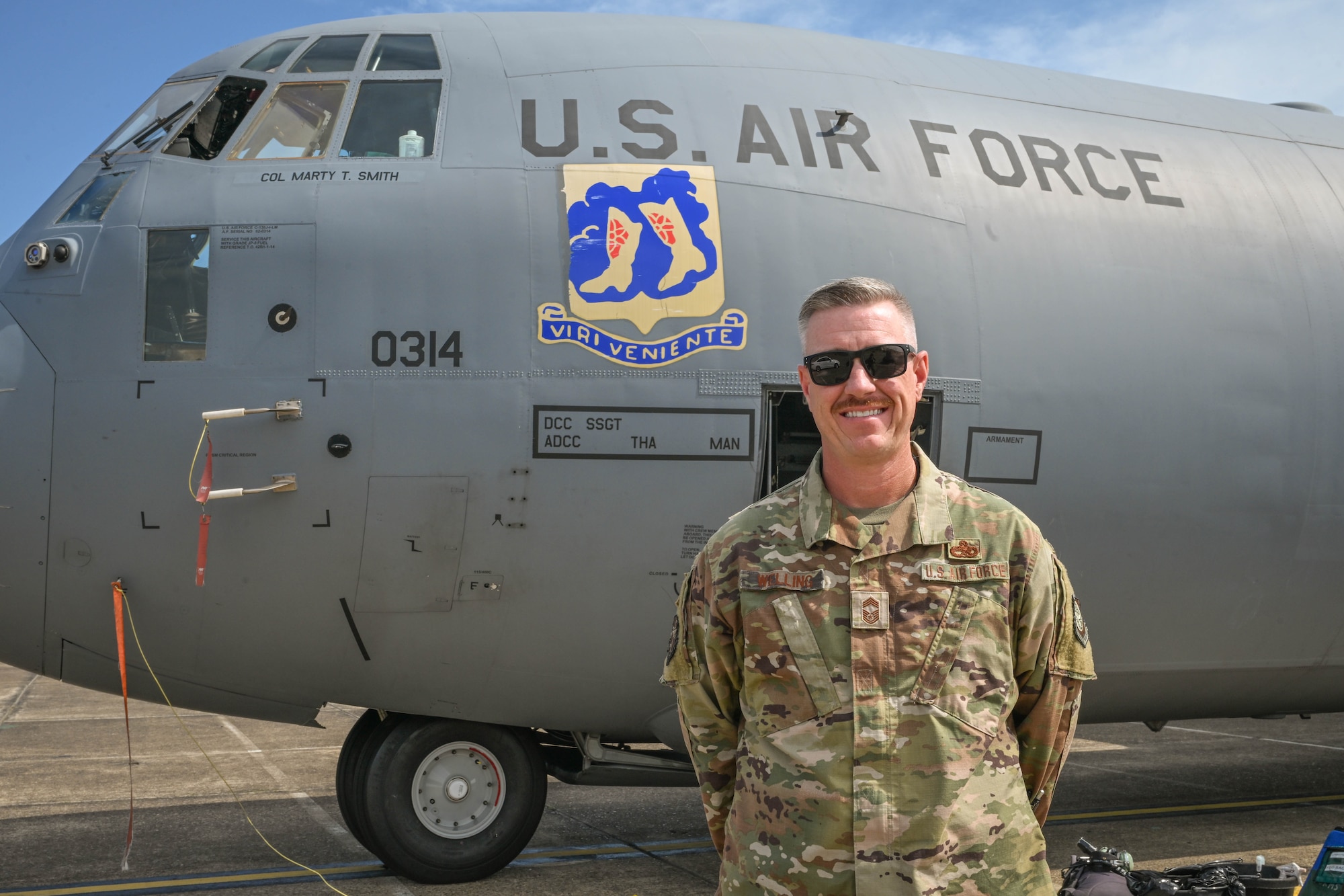 A man in uniform stands beside an aircraft.