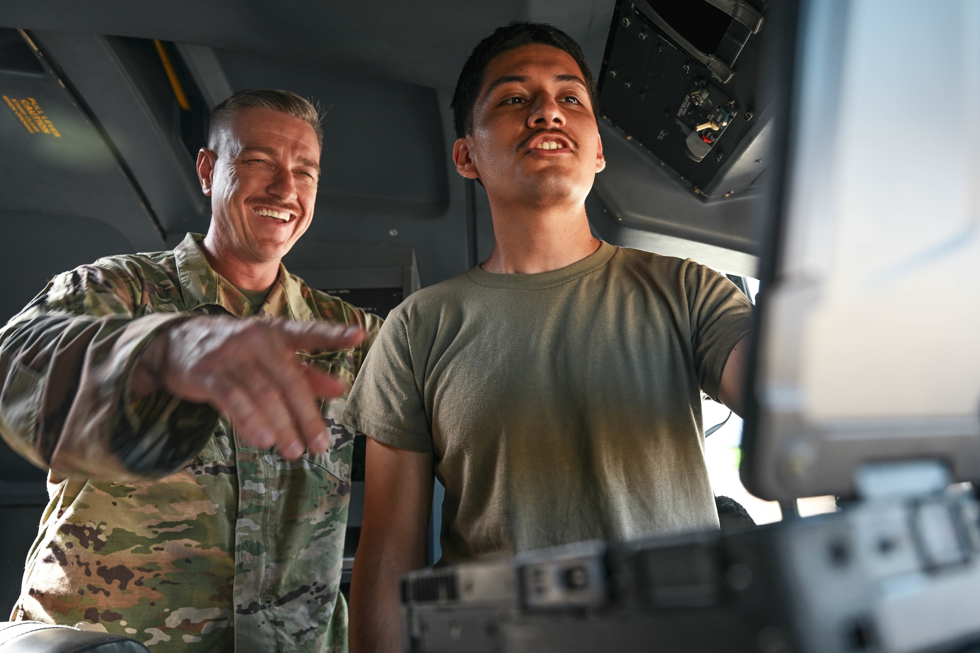 A man in uniform points to a computer alongside another man in uniform.