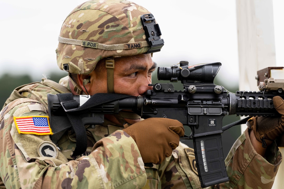 A close-up of a soldier wearing a helmet looking through the scope of a weapon.
