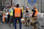 Men and a dog talk in a warehouse.