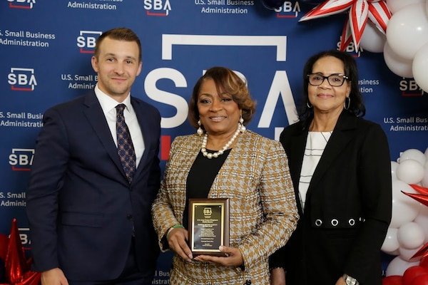 Picture of a woman receiving an award from a man and a lady.