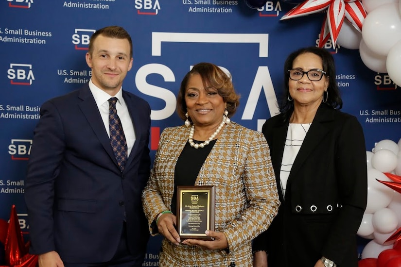 Picture of a woman receiving an award from a man and a lady.