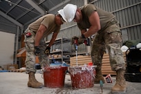 From left, U.S. Air Force Tech. Sgt. Luis Martin, and Staff Sgt. Juan Arbelo, both water and fuels systems specialists assigned to the 156th Civil Engineer Squadron, Puerto Rico Air National Guard, prepare the tiles grout for a bathroom floor tiles installation during a Deployment for Training (DFT) at Aviano Air Base, Italy, June 24, 2025.