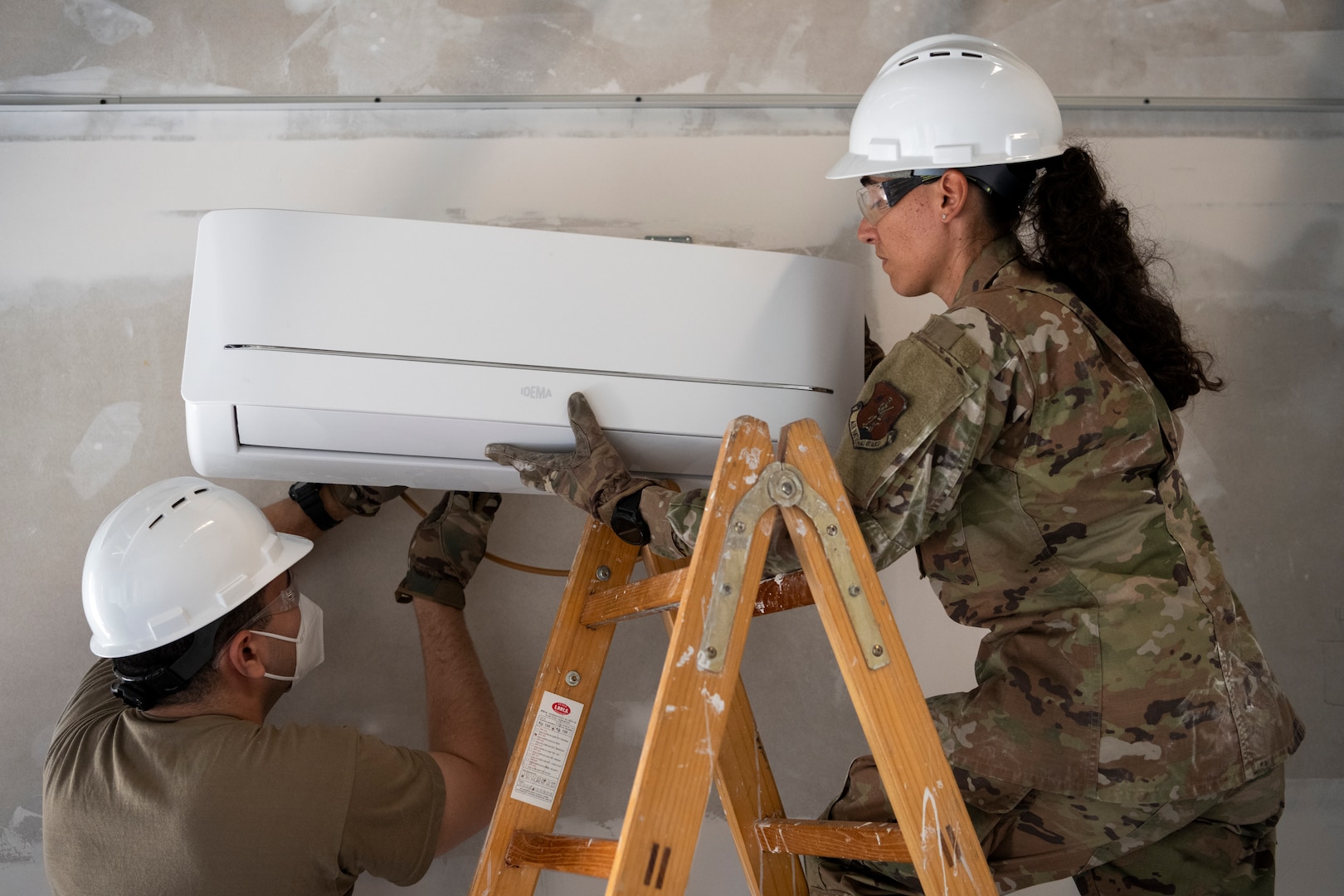 From left, U.S. Air Force Airman 1st Class Luis Cuadrado, and Airman 1st Class Llorelys Fuentes, both heat, ventilation and air conditioning/refrigeration journeymen assigned to the 156th Civil Engineer Squadron, Puerto Rico Air National Guard, install a new mini-split AC unit during a Deployment for Training (DFT) at Aviano Air Base, Italy, June 23, 2025.