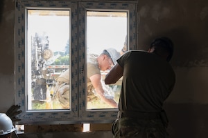 From left, U.S. Air Force Senior Airman Sebastian Rivera, and Senior Airman Wilfredo Ortega, both structural journeymen assigned to the 156th Civil Engineer Squadron, Puerto Rico Air National Guard, adjust a window frame during a Deployment for Training (DFT) at Aviano Air Base, Italy, June 23, 2025. During the DFT, the 156th CES developed their skill proficiency in a new area of responsibility while supporting real-world projects that support the U.S. European Command operations. (U.S. Air National Guard photo by Senior Airman Victoria Jewett)