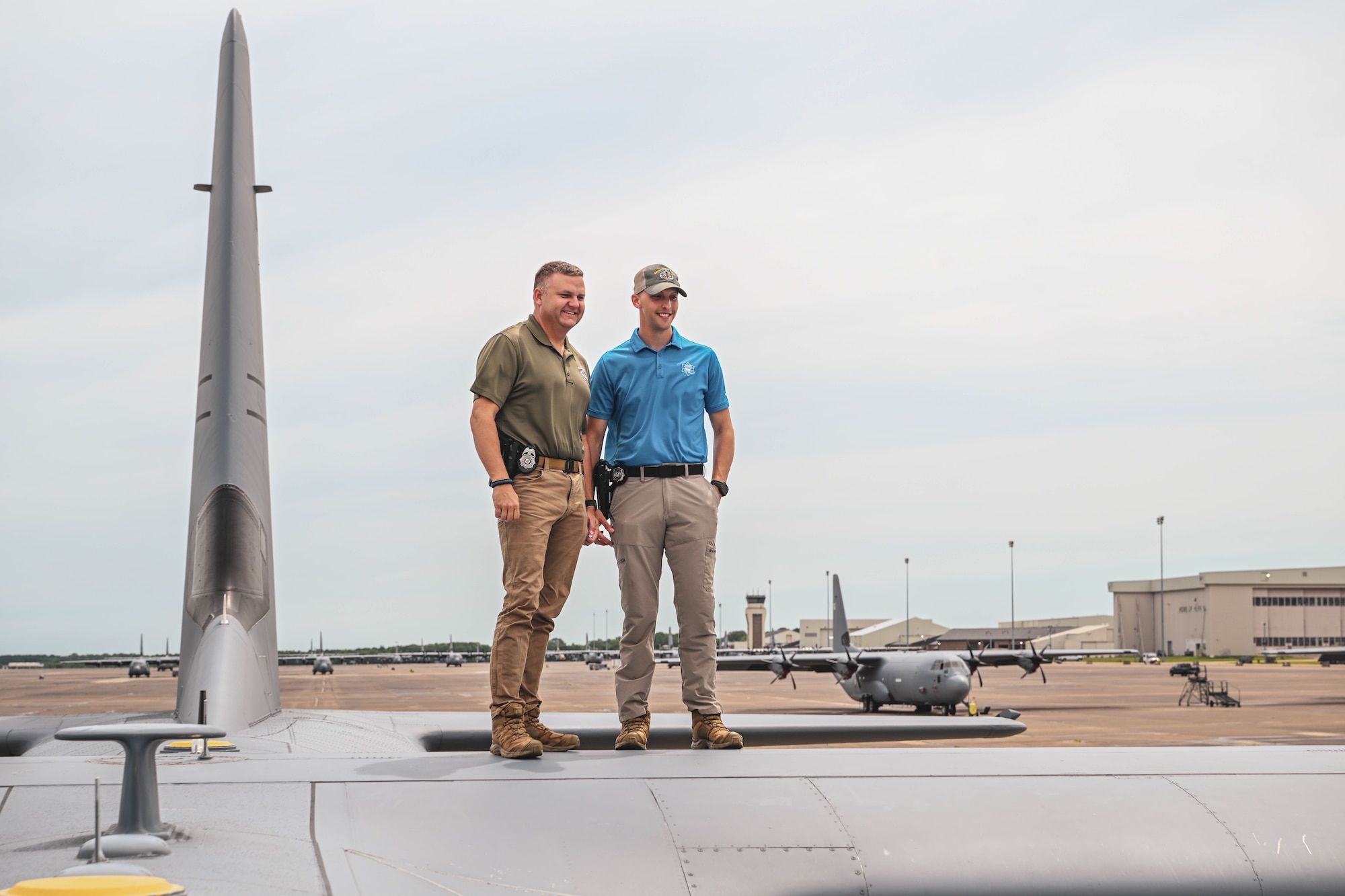 Two civilians pose for a photo on top of an aircraft.