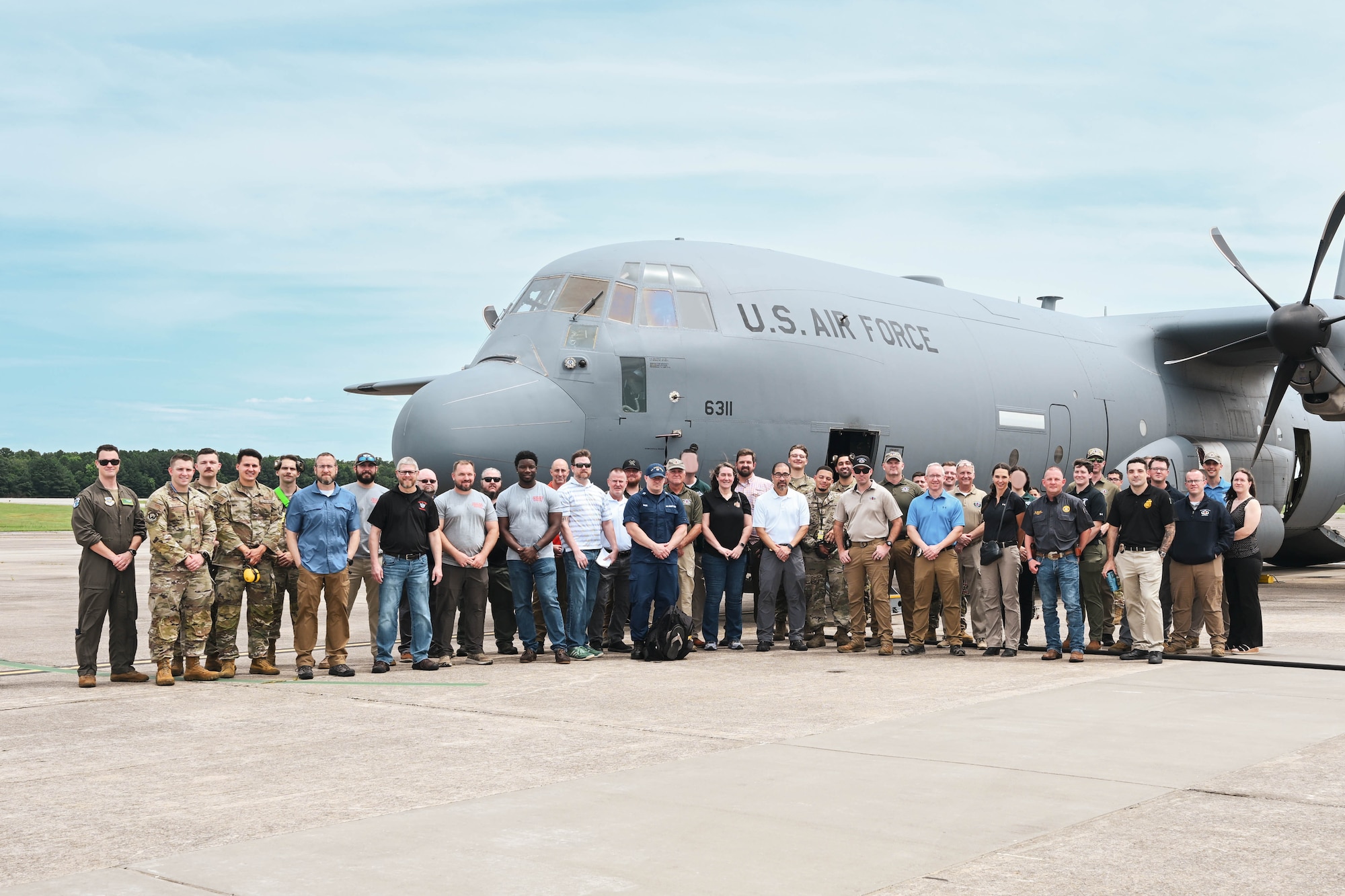 Men and women pose for a photo in front of an aircraft.