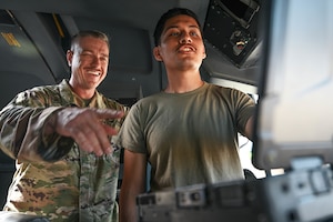A man in uniform points to a computer alongside another man in uniform.