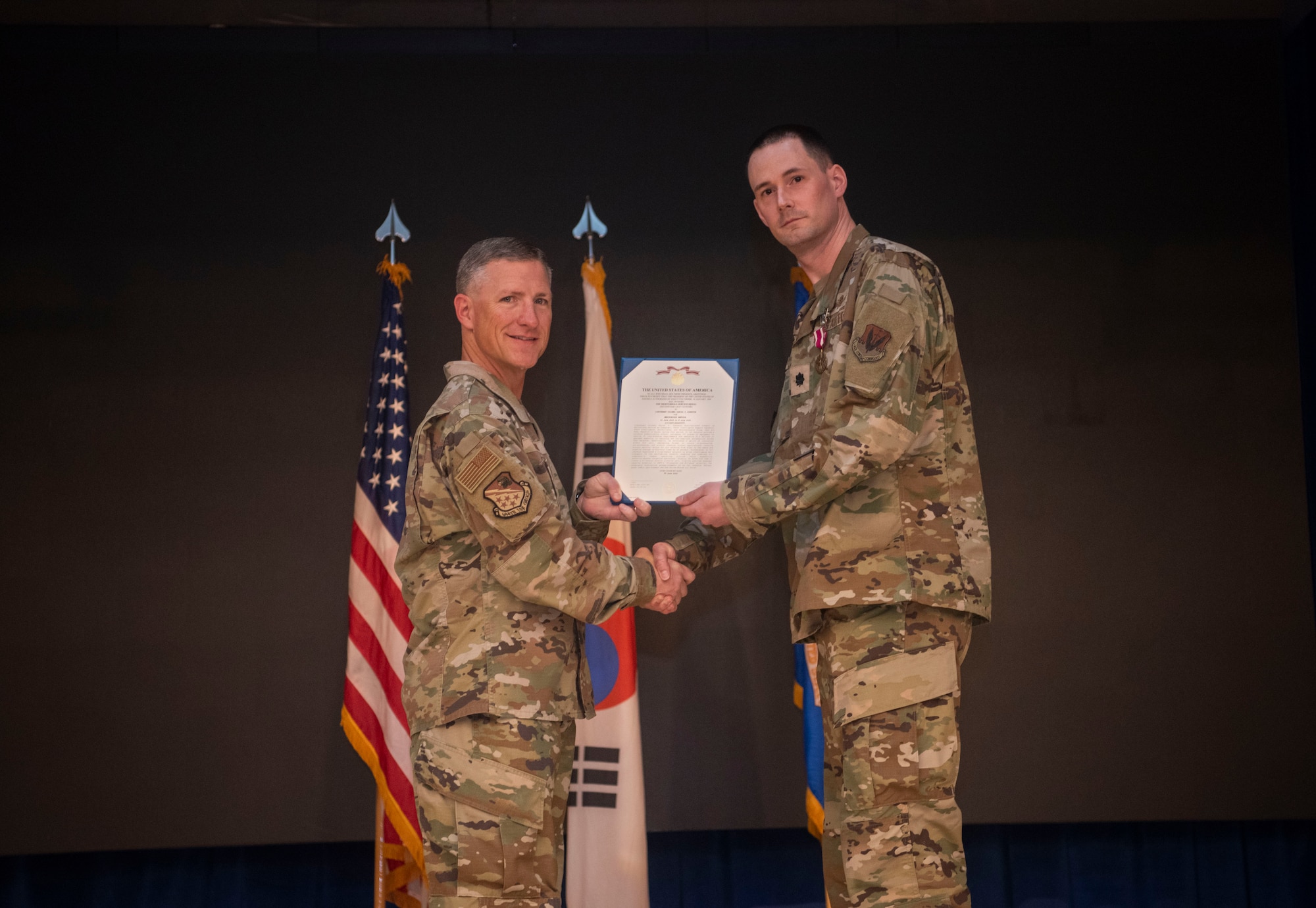 U.S. Air Force Col. Douglas Mabry, left, 694th Intelligence, Surveillance, and Reconnaissance Group commander,  presents a Meritorious Service Medal to Lt. Col. Daniel Johnston, right, outgoing 694th Intelligence Support Squadron commander, during the 694th ISS Change of Command ceremony at Osan Air Base, Republic of Korea, July 8, 2025.