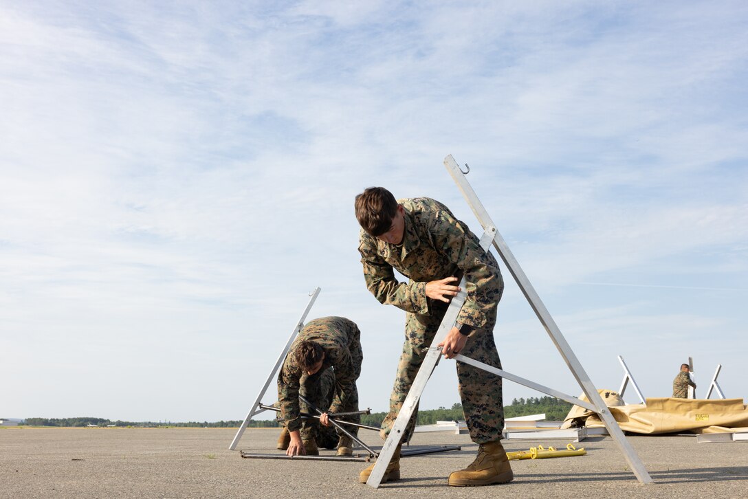 U.S. Marine Corps Pfc. Erick Avalos Rivas, left, from Georgia, and Cpl. Landon Pursley, both bulk fuel specialists with Marine Wing Support Squadron (MWSS) 273, set up metal frames for a forward arming and refueling point at Bangor International Airport, Maine, July 6, 2025. Atlantic Alliance 2025 (AA25) is the premier East Coast naval integration exercise, featuring over 25 U.S. Navy and Marine Corps units alongside Dutch naval forces and British Royal Commandos. Spanning from North Carolina to Maine, AA25 will showcase a range of dynamic events including force integration, air assault operations, bilateral reconnaissance, naval strait transits, amphibious assault training, and a simulated war-at-sea exercise. (U.S. Marine Corps photo by Lance Cpl. Orlanys Diaz Figueroa)