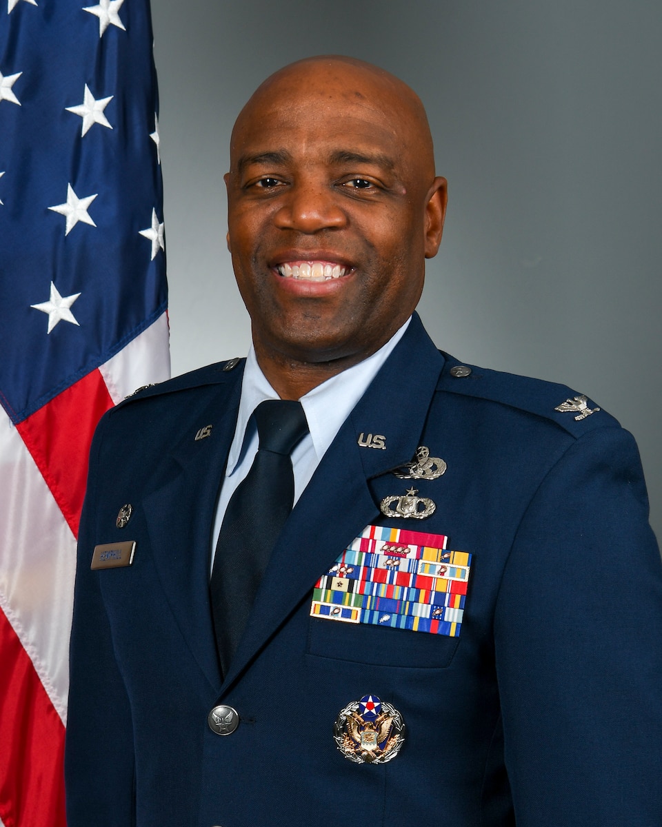 Posed photo of man in military uniform with U.S. flag in background