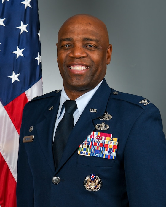 Posed photo of man in military uniform with U.S. flag in background
