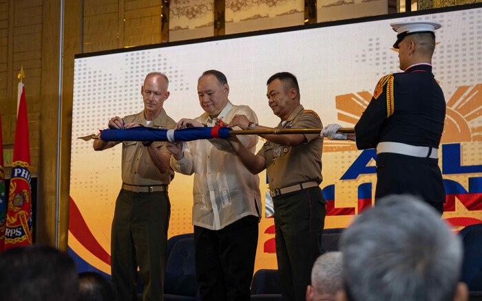 From left to right, U.S. Marine Corps Lt. Gen. James Glynn, commander, U.S. Marine Corps Forces, Pacific, Philippines Secretary of National Defense Gilberto Teodoro Jr., and the 37th Commandant of the Philippine Marine Corps, Maj. Gen. Vicente Blanco, unfurl a flag during the opening ceremony of the 11th iteration of the Pacific Amphibious Leaders Symposium, Manila, Philippines, July 8, 2025. Bringing together experts and leaders from across the Indo-Pacific, PALS fosters collaboration among Allied and partner amphibious and maritime forces to share knowledge and recent operational insights. This year’s symposium hosted senior leaders from 22 participating nations who are committed to a free and open Indo-Pacific, with the objective of strengthening and developing regional relationships. (U.S. Marine Corps photo by Lance Cpl. Moses S. Lopez Franco)