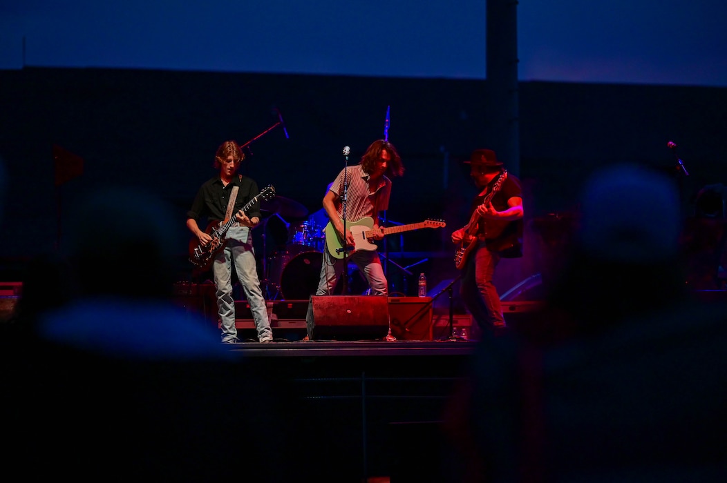 Three guys play guitar.