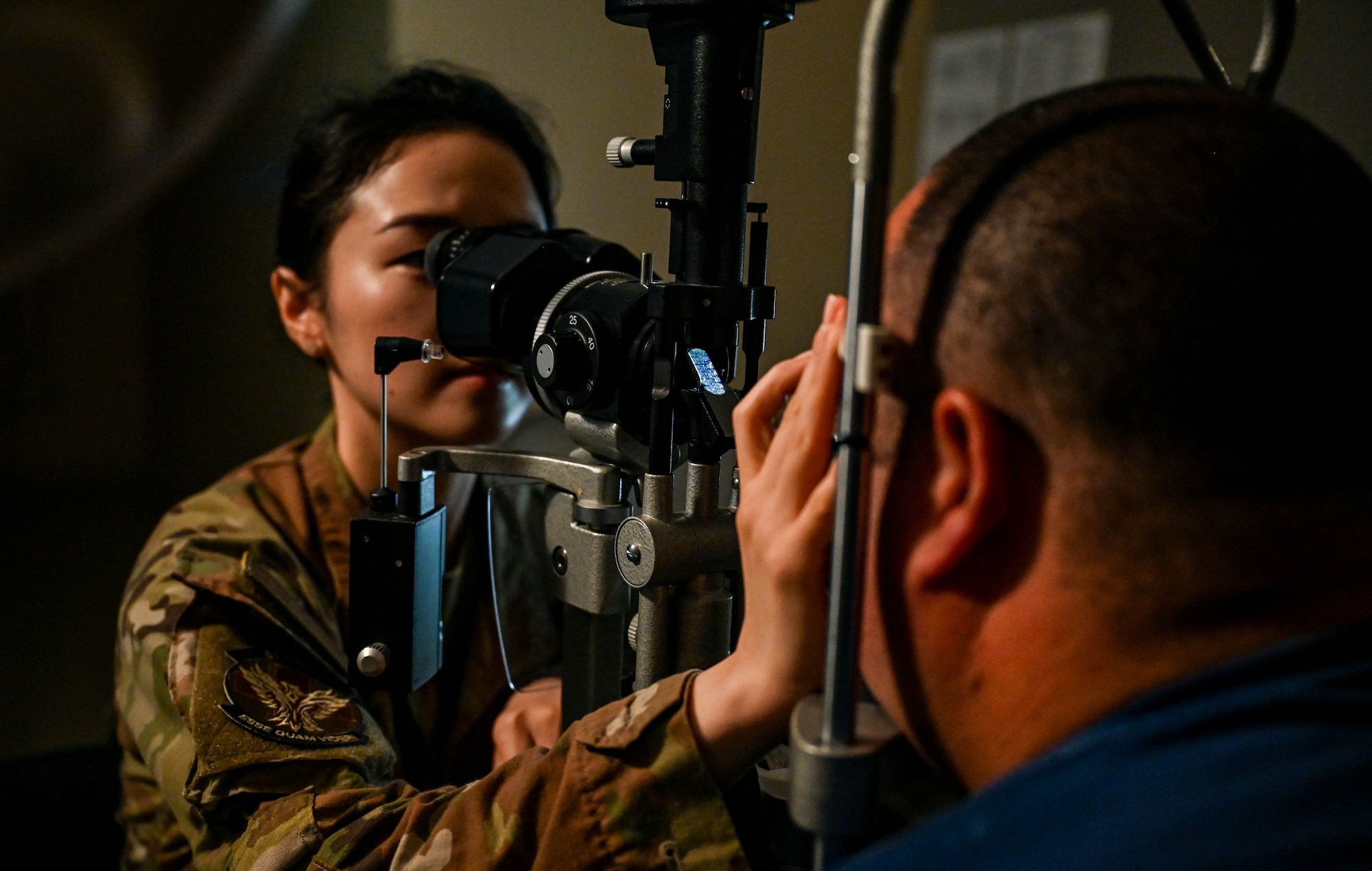 A woman's hands holding a magnifying glass to view a man's dilated pupils.