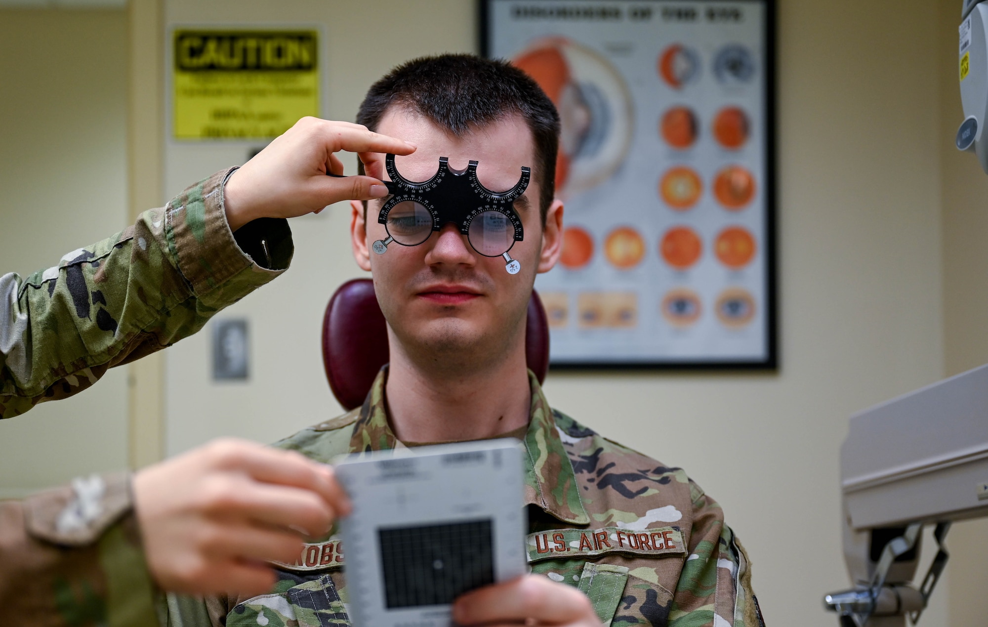 A man in military uniform looks through a pair of trial eye glass lenses.