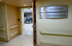 A yellow wall and doorway with two silver signs reading Optometry & Ophthalmology.