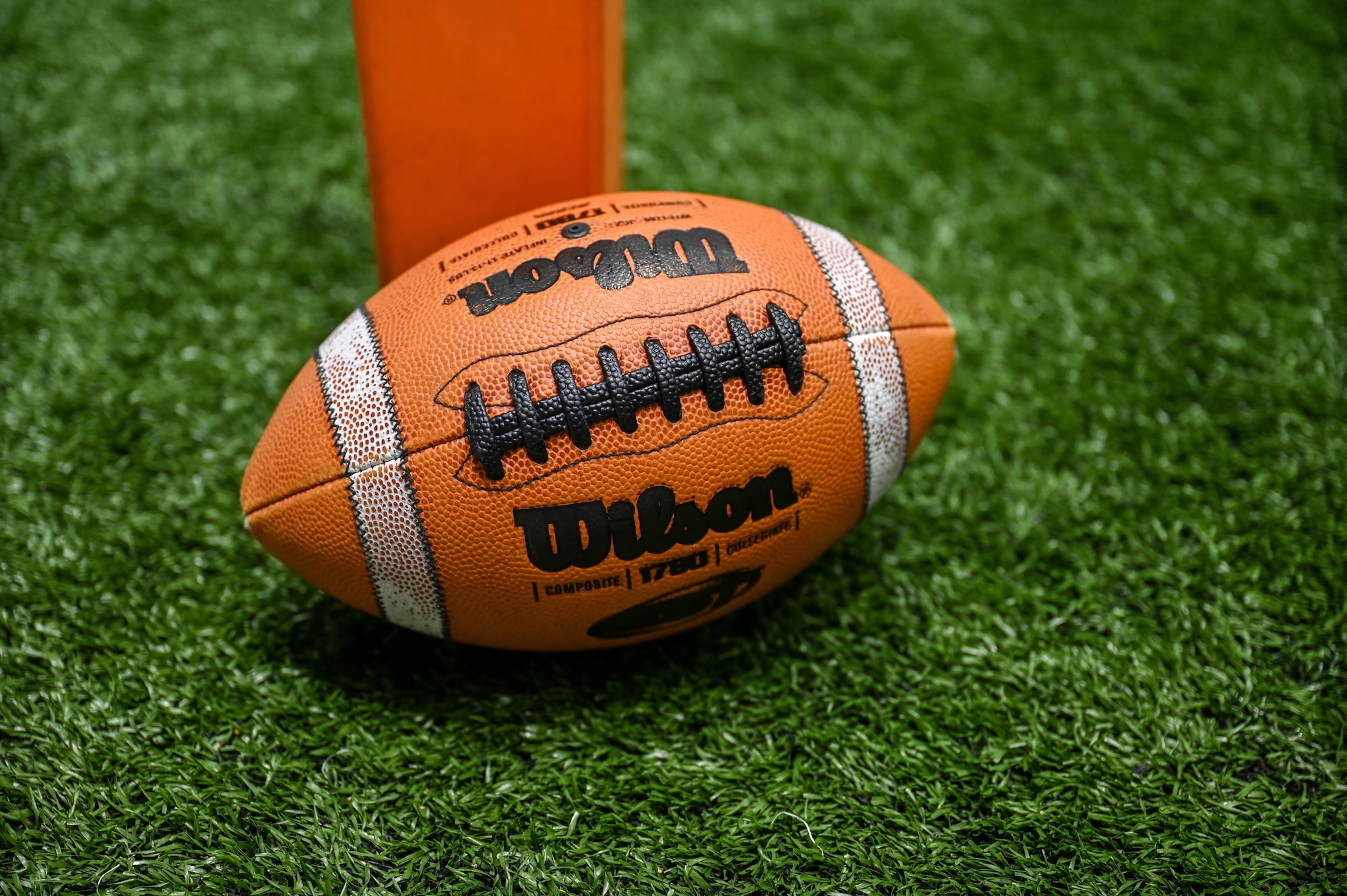 A light brown football sits on a patch of green turf.
