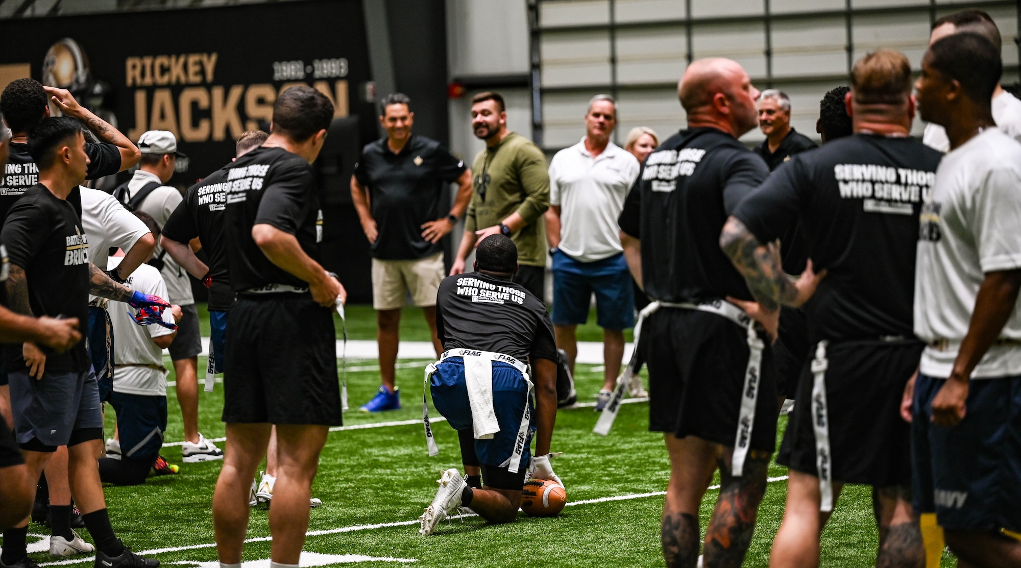 A group of people in athletic gear stand on an indoor turf field.