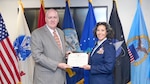 A man hands a certificate to an Air Force Colonel