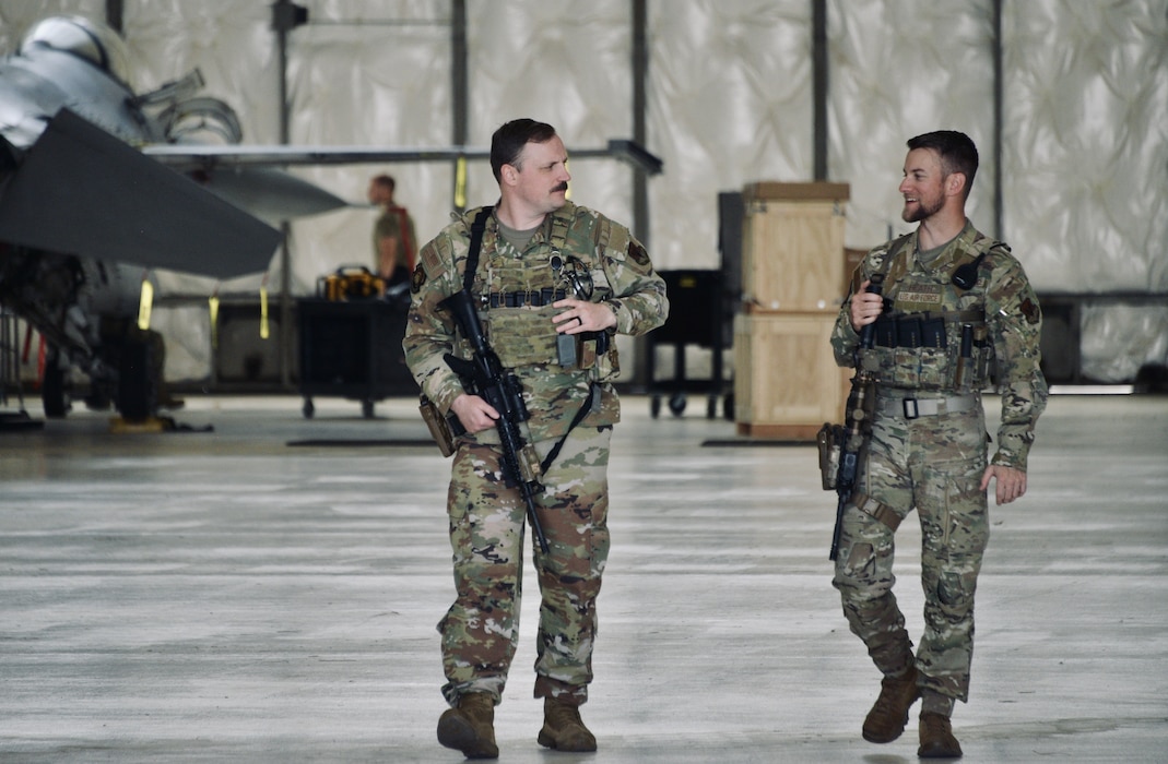 Two airmen from Security Forces Squadron patrol flight hangar.