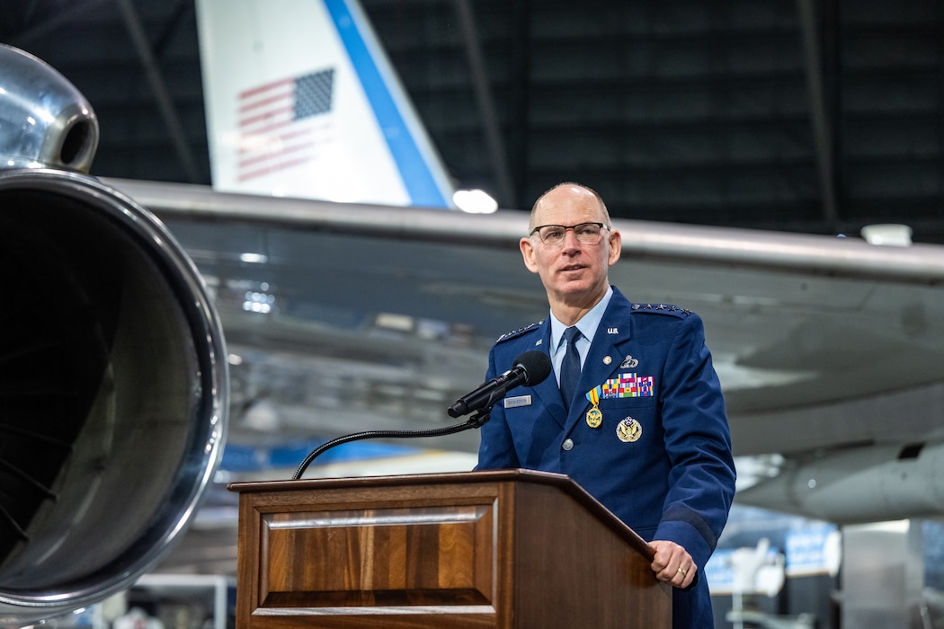 Gen. Richardson stands behind a mic and podium wearing a service dress uniform