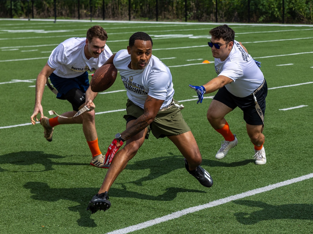 U.S. Marine Corps Master Sgt. Kevin Thompson, a Marine Air Ground Tactical Force planner with Headquarters Battalion, Marine Forces Reserve, powers the football through the U.S. Coast Guard’s defense during the Battle of The Branches at the New Orleans Saints Practice Facility, Metairie, Louisiana, July 1, 2025. Battle of The Branches consisted of multiple events, the event consisted of flag football, tug-of-war, 40-yard dash, sprint relay, distance throwing and a push up competition. (U.S. Marine Corps photo by Cpl. Aaron TorresLemus)